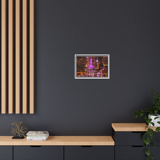 Framed artwork of a cityscape with a pink building on a dark gray wall.
